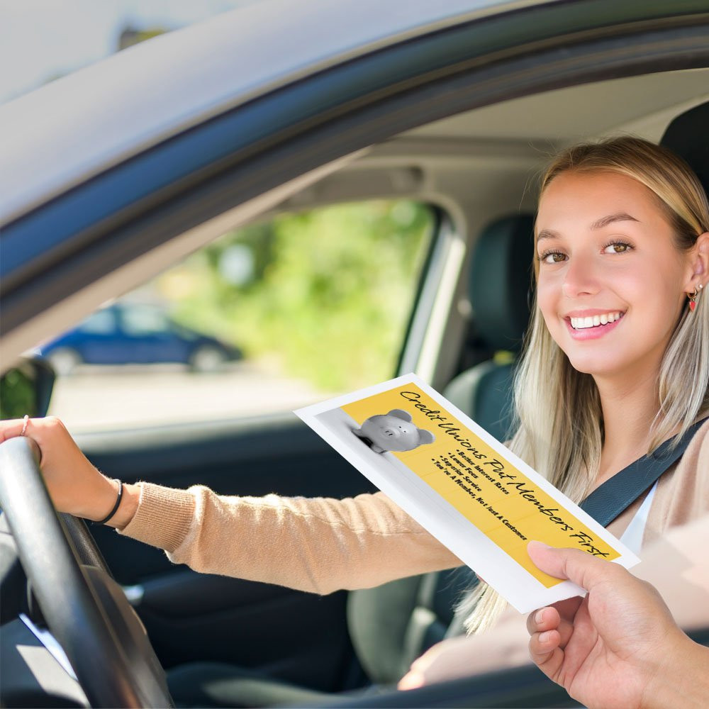 Bank customer at teller window receiving drive up money envelope 