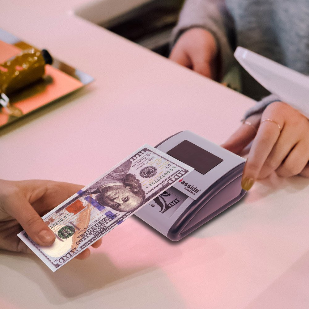 Cassida InstaCheck Counterfeit Detector shown scanning money  shown in use at checkout counter 