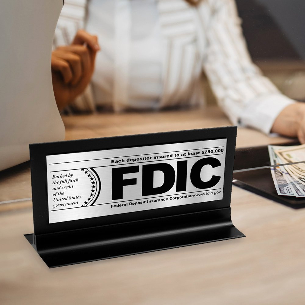 FDIC $250000 Framed Counter Sign - Brushed Aluminum w/ Black Text Shown Displayed On CounterTop